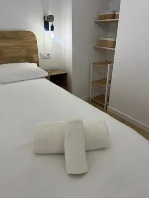 a bedroom with a white bed with two pillows at Apartamento acogedor frente a Plaza del Cedro in Valencia