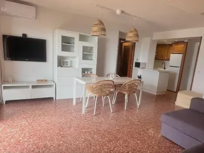 a living room with a table and chairs and a television at Florazar 2 Apartamento frente al mar en Cullera in Cullera