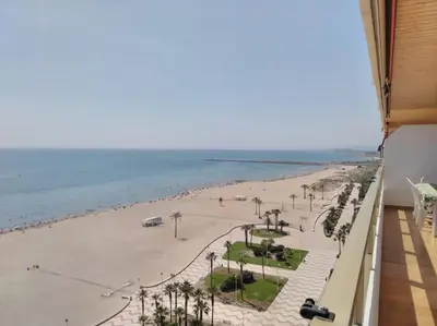 two white chairs on a balcony with a view of the ocean at Apartamento frente a la playa in Cullera