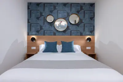 a bedroom with a large bed with blue pillows at Smartr Valencia Turia in Valencia