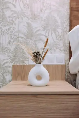 a white vase with some flowers in it on a table at Nuevo y moderno loft en amistat in Valencia