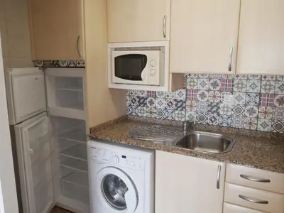 a small kitchen with a washing machine and a microwave at Malvarrosa, 8-54 in Cullera