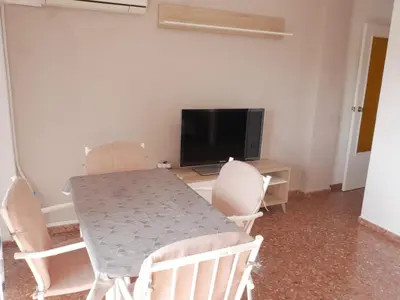 a dining room table with chairs and a television at Malvarrosa, 8-54 in Cullera