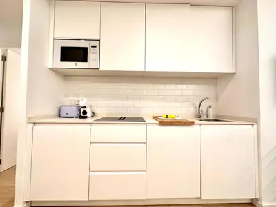 a white kitchen with white cabinets and a microwave at Apartamento Hierros VLC in Valencia
