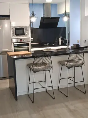a kitchen with two bar stools at a counter at Alice Home in Puebla de Farnals