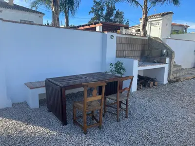 a table and two chairs next to a white wall at Villa con piscina en la montaña in Llombay