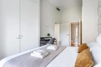 a white bedroom with a bed with towels on it at Valencia City Apartment with Gym Pool Free Parking TheHavenEscape in Valencia