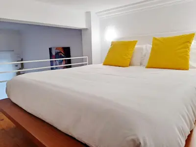 a large white bed with two yellow pillows on it at Loft DobleAltura Escalante in Valencia