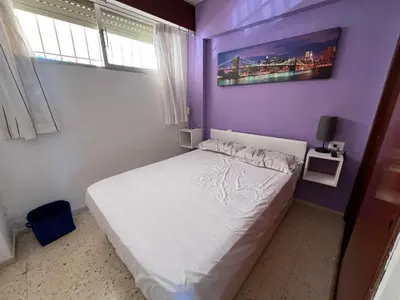 a bedroom with a white bed and a purple wall at El Prado - Primera Línea Playa Cullera in Valencia
