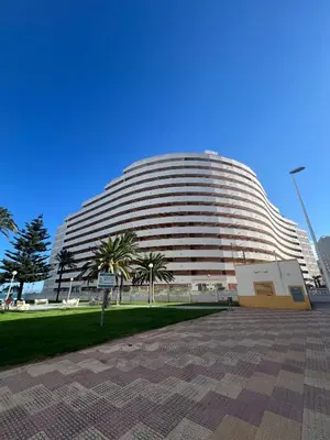 a large building with palm trees in front of it at El Prado - Primera Línea Playa Cullera in Valencia