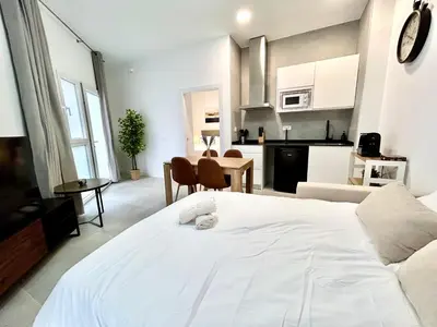 a bedroom with a large white bed and a kitchen at Strategic Stay-Unlock Valencia's Best-Kept Secret in Valencia