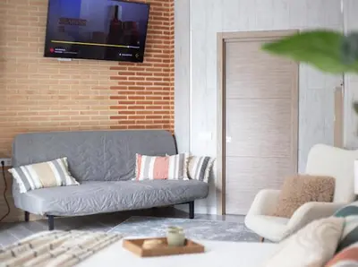 a living room with a couch and a tv on a brick wall at New Light Cozy Stay Ruzafa in Valencia
