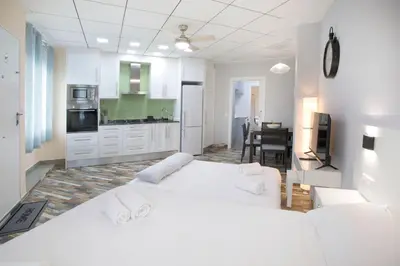 a white room with two beds and a kitchen at District Key - Carricola in Valencia