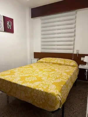 a bedroom with a bed with a yellow comforter at Los Olivos BB1 in Faro de Cullera