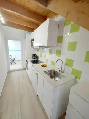 a kitchen with white cabinets and green and white tiles at Maravillosa casa junto al mar y cerca del centro in Valencia