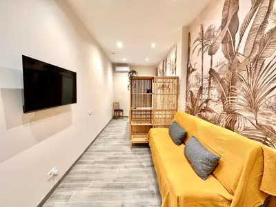 a living room with a yellow couch and a flat screen tv at Lofts Casa Tropicana in Valencia