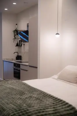 a white bedroom with a bed and a kitchen at Green Luxury Zamenhof in Valencia