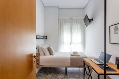 a bedroom with a bed and a desk with a laptop at Zalamera BnB in Valencia
