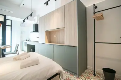 a bedroom with a bed and a kitchen with a table at District Key - Valencia, Olimpia 2 in Valencia