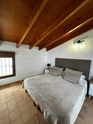 a bedroom with a large bed with a wooden ceiling at Casa Durá in Chulilla