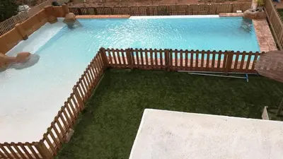 a large swimming pool with a wooden fence and water at La villa de Naomi in Chella