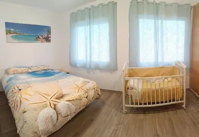 a bedroom with a crib and two windows at Cozy townhouse in Soneja in Soneja