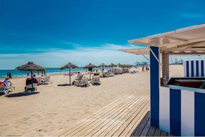 a beach with chairs and umbrellas and the ocean at El Cabañal 400 meters from the Beach in Valencia