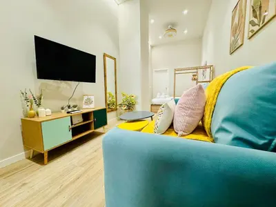 a living room with a blue couch and a flat screen tv at Stylish Studio near City Center in Valencia