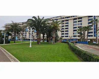 a park with palm trees in front of a building at Playa La Patacona in Valencia