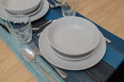 a table with white plates and silverware on a blue napkin at Loft bien equipado - Lavavajillas, tostadora, secador, in Valencia