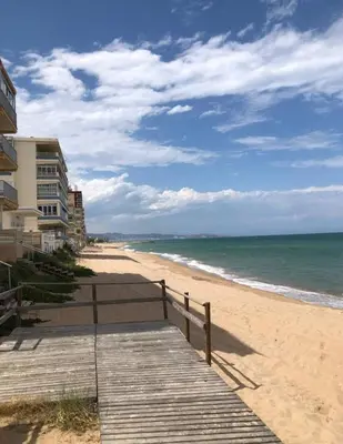 a wooden boardwalk leading to a beach with a building at arena y mar in Tavernes de Valldigna