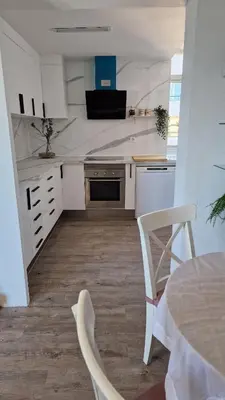 a kitchen with white cabinets and a table and chairs at arena y mar in Tavernes de Valldigna
