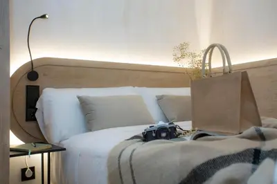 a camera on a bed with a bag on it at Nomad Haux Mestalla Room 101 in Valencia