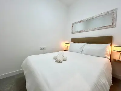 a bedroom with a large white bed with two lamps at Valencia Comfort Stay Near Metro, 2 Bed, 1 Bath in Valencia