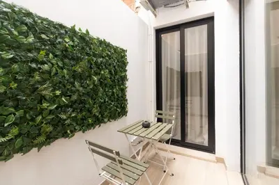 a table and chairs on a balcony with a green wall at GuestReady - Urban elegance in Valencia in Valencia