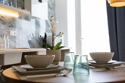 a table with plates and glasses and a flower on it at UY - Loft Valencia Acogedores y modernos estudios cerca de la estación Joaquín Sorolla in Valencia