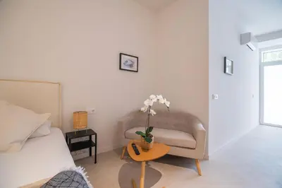 a bedroom with a bed and a chair and a table with flowers at LO - Loft Valencia - Modernos y acogedores estudios cerca a las Artes y las Ciencias in Valencia