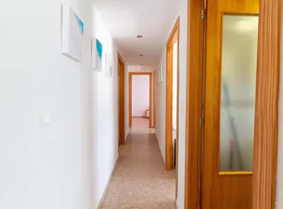 a hallway with white walls and wooden doors at Global Vacacional, Apartamento de 3 habitaciones en urbanización cerca del mar in Canet de Berenguer
