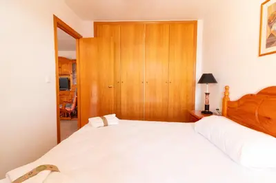 a bedroom with a white bed and a wooden cabinet at Global Vacacional, Acogedor apartamento en Canet de Berenguer in Canet de Berenguer