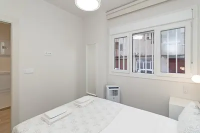 a white bedroom with a bed and two windows at GuestReady - One lovely home in Valencia in Valencia