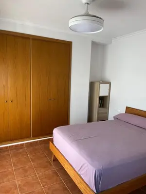 a bedroom with a bed and wooden cabinets at Casa Platja Mareny Blau in Mareny Blau