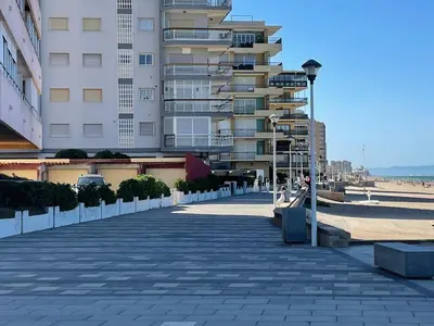 a sidewalk next to a beach with a tall building at Casa Platja Mareny Blau in Mareny Blau