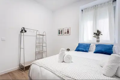 a white bedroom with a large bed with blue pillows at Lugre, Lovely flat close to center in Valencia
