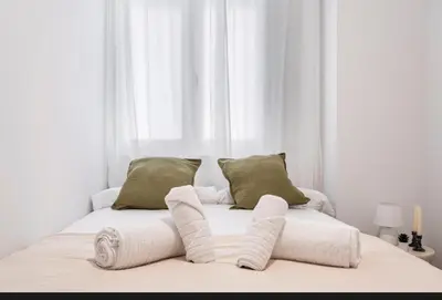 a white bed with two pillows and towels on it at Lugre, Lovely flat close to center in Valencia