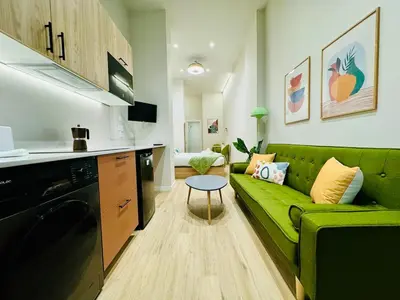 a living room with a green couch and a kitchen at Stylish Design Studio in Valencia in Valencia