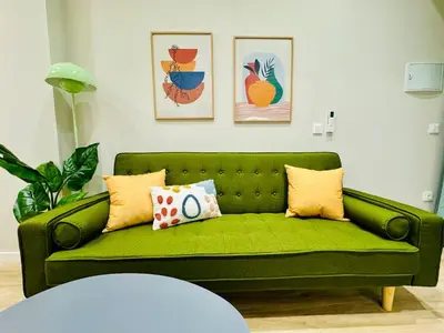 a green couch in a living room with paintings at Stylish Design Studio in Valencia in Valencia