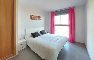 a bedroom with a bed and a window with pink curtains at Cozy Apartment In Moncofa in Moncófar