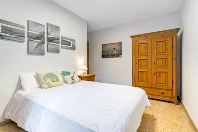 a bedroom with a white bed and a wooden cabinet at Centrally located temporary, very spacious Pataconabluerentals in Valencia