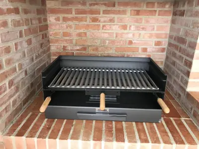 a grill in a brick wall with two wooden tongs at Villa conectada al mediterraneo, Infinity pool in Faro de Cullera