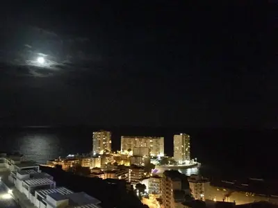 a view of a city at night with a full moon at Villa conectada al mediterraneo, Infinity pool in Faro de Cullera